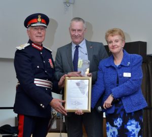 Image of Lord Lieutenant of West Midlands and Beacon Volunteer holding the Queens Award. 