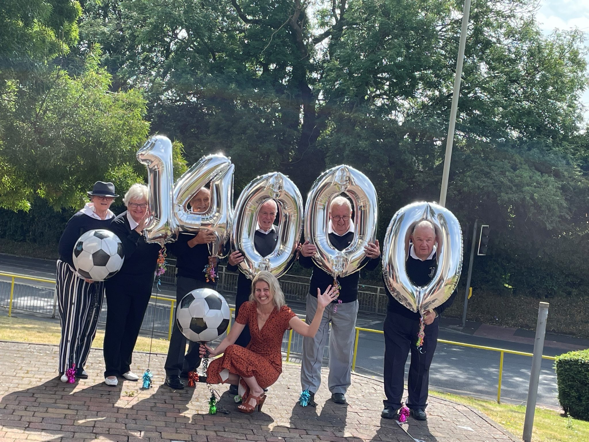 This shows organisers of the JW Hunt Cup with Kathy Roper, chair of trustees at Beacon with Chief Executive Lisa Cowley. They are holding inflatable balloons that spell 14,000 