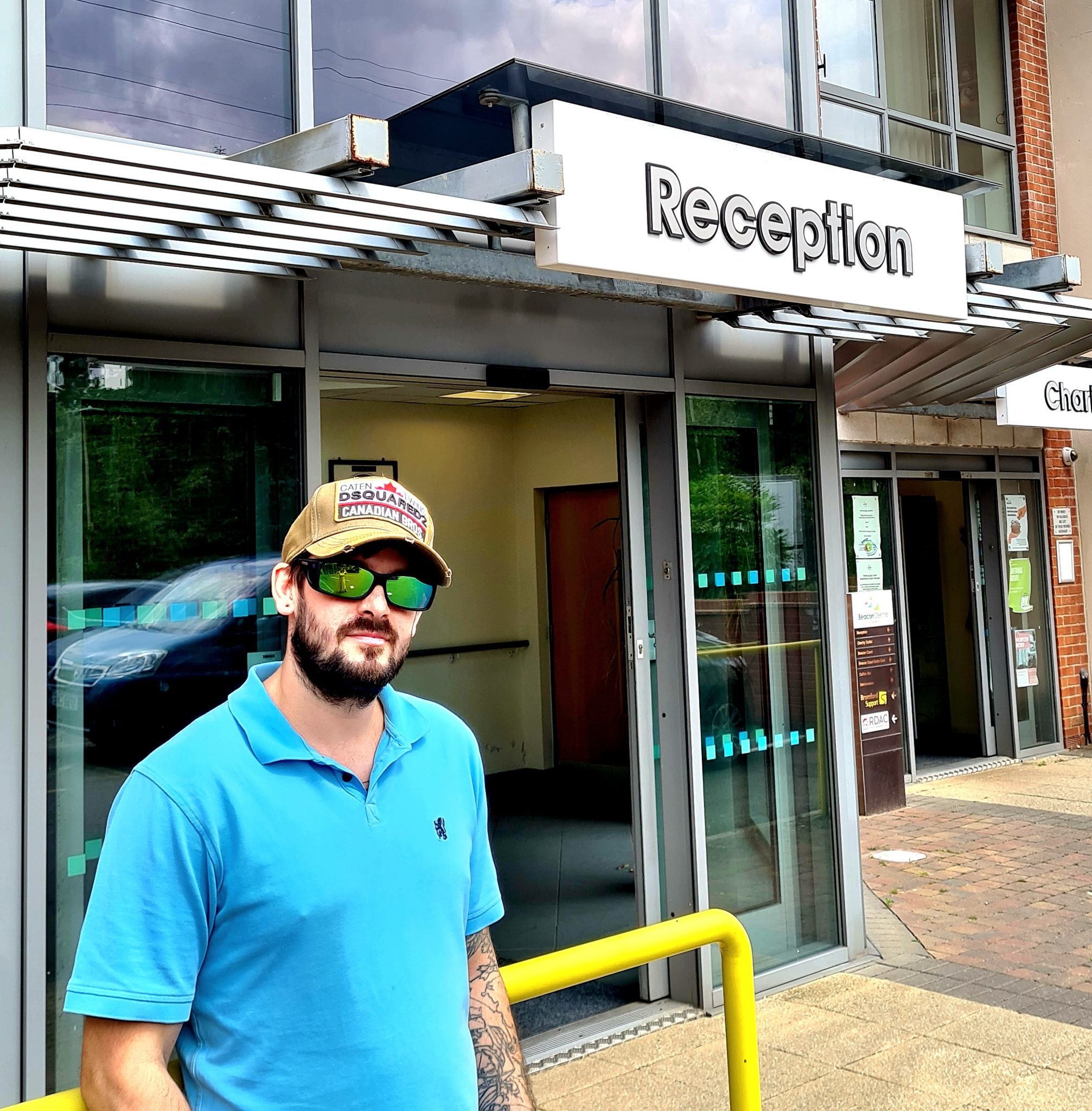 This shows our sight loss advisor Nathan, outside our centre in jeans, a blue polo shirt, a cap and of course, sunglasses!
