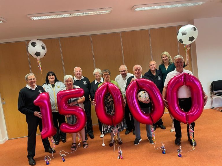 Members of the JW Hunt Cup team with representatives of Beacon and Wolves holding giant pink balloons that spell out 15,000.