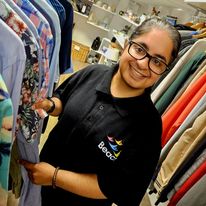 This shows a volunteer in our Bilston shop. She's wearing a black Beacon polo t-shirt and has dark hair in a pony tail and is wearing glasses.