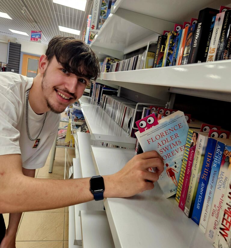 This shows Jarad, Assistant Manager from our Sedgley shop pulling a book from our bookshelf.