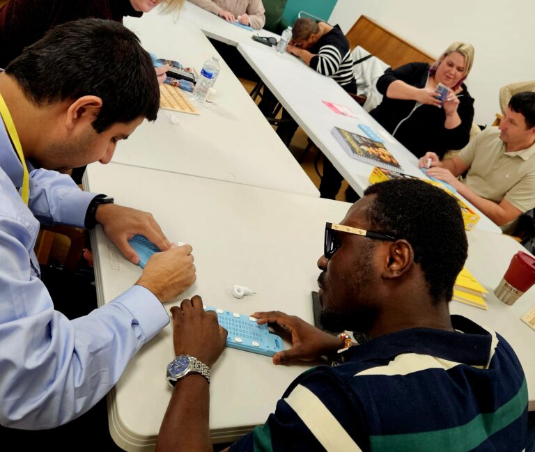 This shows a group of people sat around a table completing a braille course at beacon.