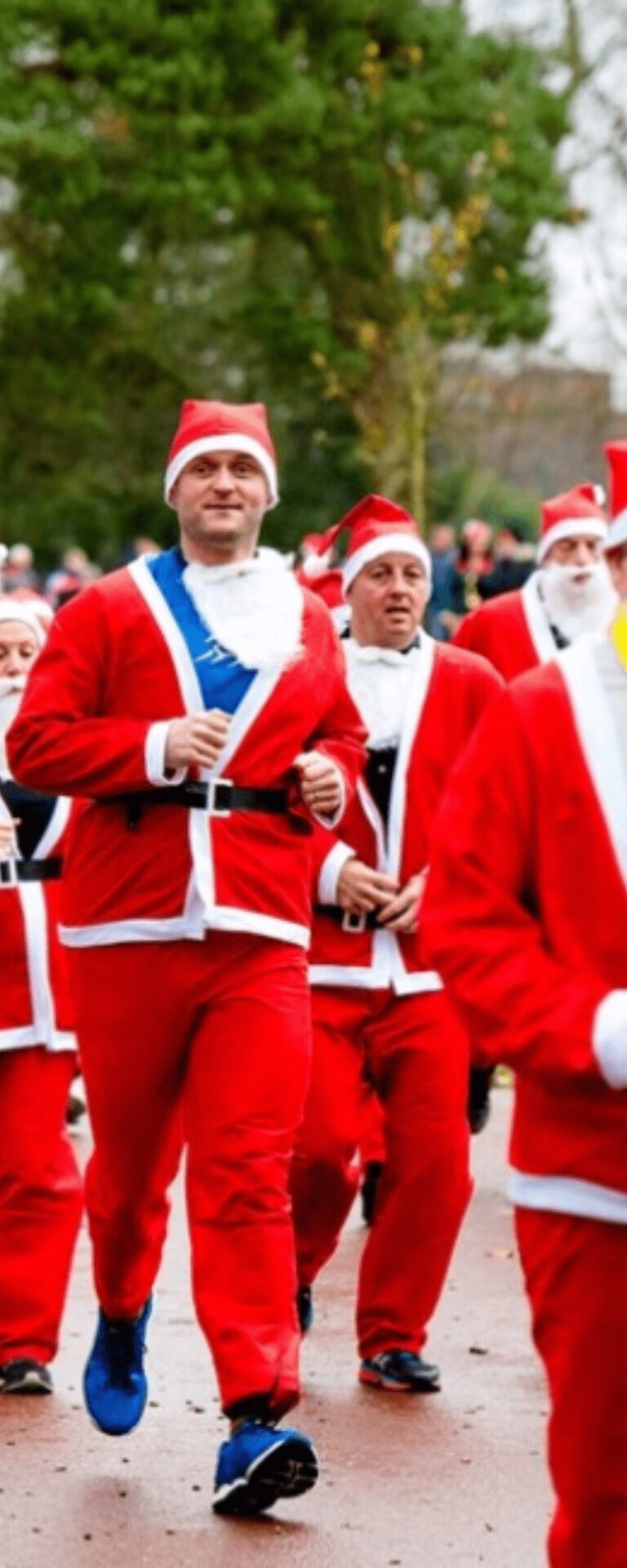 A group of runners dressed in red Santa suits and hats running around the course.